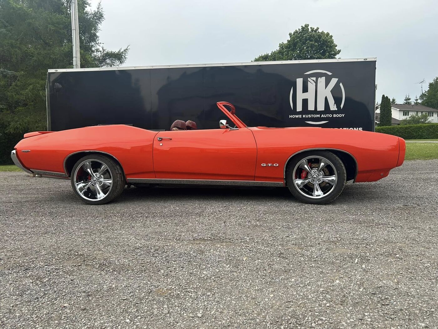 Orange convertible muscle car beside the Howe Kustom trailer